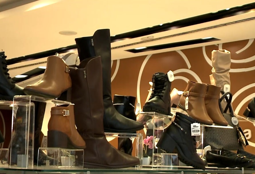 Imagem de botas exibidas em prateleira de loja.