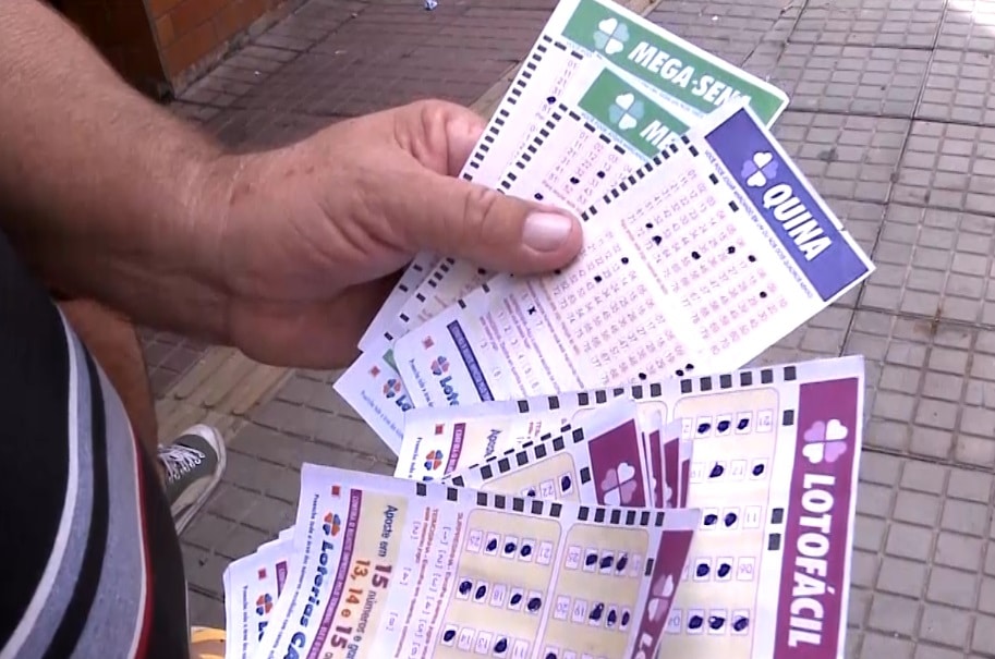 Pessoa segurando cartelas da Lotof&aacute;cil.
