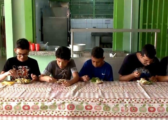Crian&ccedil;as realizando almo&ccedil;os nas f&eacute;rias em escola.
