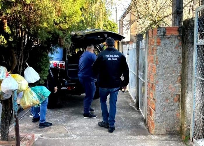 Agentes da pol&iacute;cia pr&oacute;ximo de uma viatura.