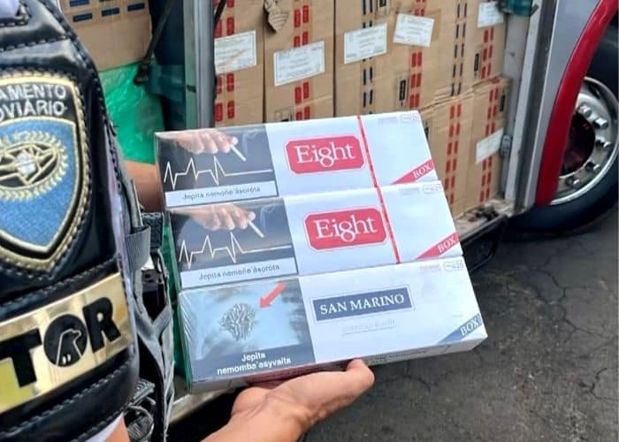 Policial segurando ma&ccedil;os de cigarro.