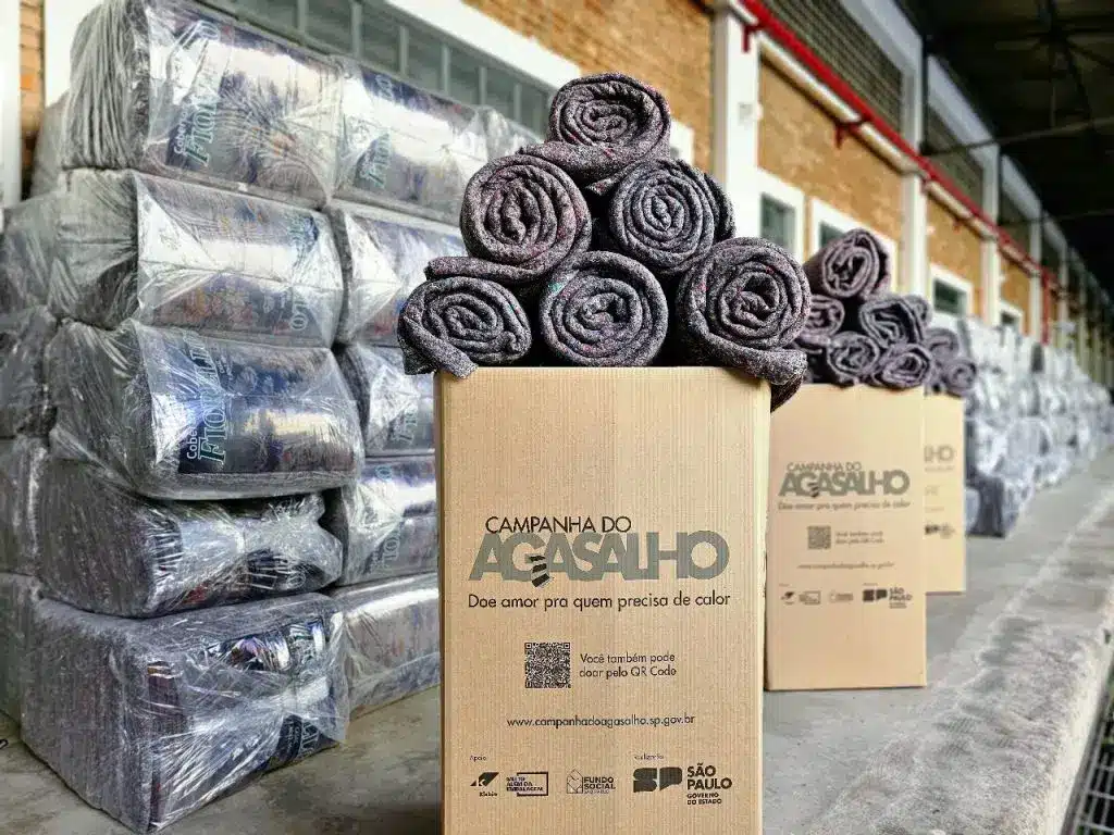 Imagem de cobertores em cima de uma caixa de papel&atilde;o onde ficam as doa&ccedil;&otilde;es