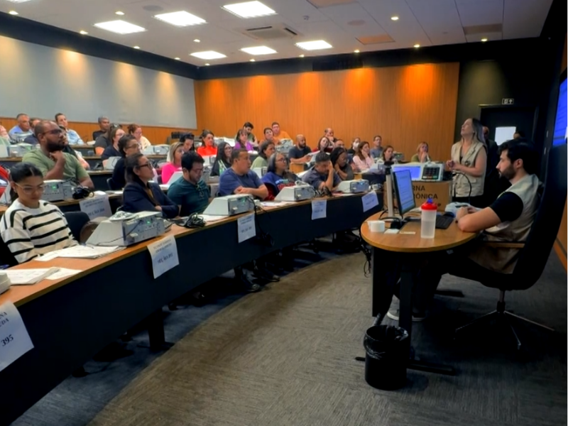 Imagem de sala de aula de universidade com pessoas sentadas e reunidas.