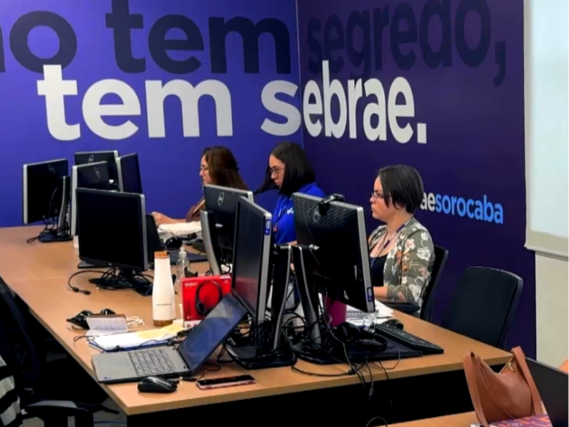 Mulheres sentadas em mesa e mexendo nos computadores.