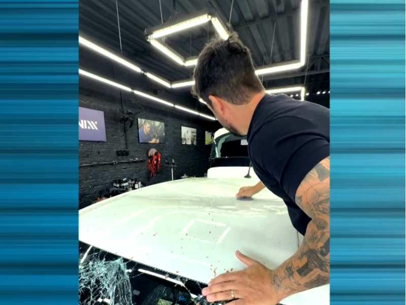 Imagem de homem realizando o servi&ccedil;o de martelinho de ouro em teto de um carro branco.